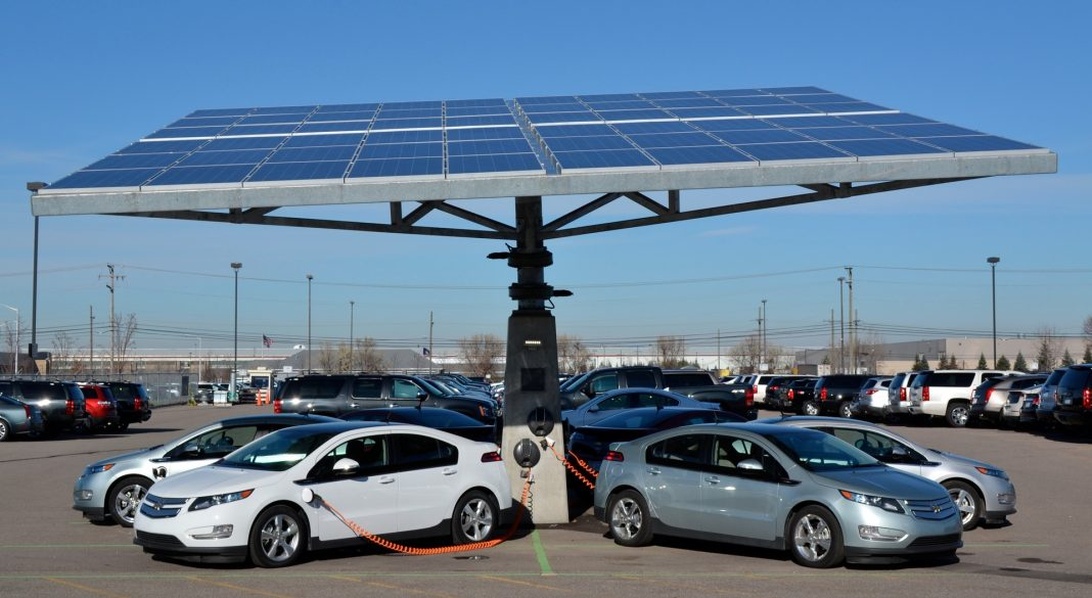 En kommersiell laddstation med solpaneler som laddar flera elbilar, vilket illustrerar integrationen av fordon i ett större energisystem.